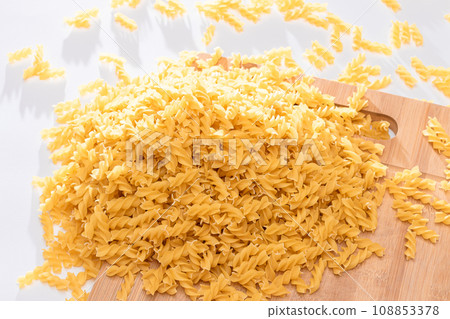Uncooked Fusilli Pasta Scattered on Wooden Board Uncooked Fusilli Pasta Scattered on Wooden Board 108853378
