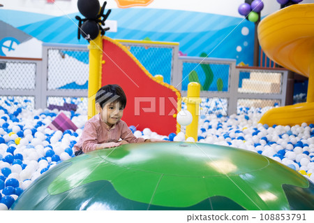 Little Asian boy looking at a floating ball Among many small balls Little Asian boy looking at a floating ball Among many small balls 108853791