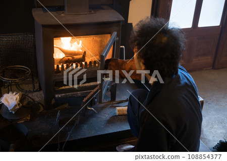 A man putting firewood into a wood-burning stove - An image of preparing for winter in Japan's winter countryside A bird's-eye view of the true and careful way of life A man putting firewood into a wood-burning stove - An image of preparing for winter in Japan's winter countryside A bird's-eye view of the true and careful way of life 108854377
