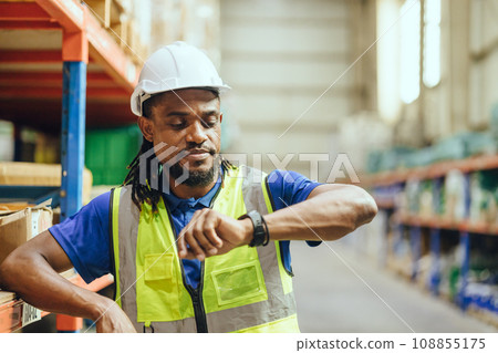 African Black people Engineer male worker looking at wristwatch time check. Industry factory working hours afternoon break times for lunch 108855175