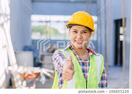 Asian woman construction worker happy smiling thumbs up at building construction site background 108855220