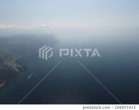Aerial view from above on calm azure sea and volcanic rocky shores. Small waves on water surface in motion blur. Nature summer ocean sea beach background. Nobody. Holiday, vacation and travel concept Aerial view from above on calm azure sea and volcanic rocky shores. Small waves on water surface in motion blur. Nature summer ocean sea beach background. Nobody. Holiday, vacation and travel concept 108855433