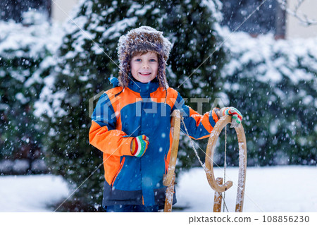 Little kid boy having fung with sleigh ride in winter 108856230