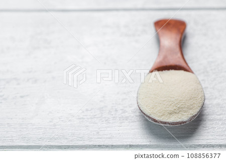 Collagen powder in spoon on wooden white background. Extra protein intake. Natural beauty and health supplement. Flat lay, top view Collagen powder in spoon on wooden white background. Extra protein intake. Natural beauty and health supplement. Flat lay, top view 108856377