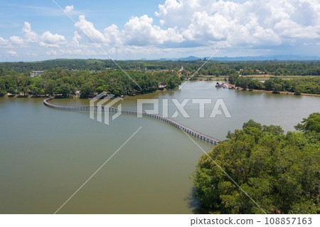 Aerial top view of a bridge with garden park with green mangrove forest trees, river, pond or lake. Nature landscape background, Thailand. Aerial top view of a bridge with garden park with green mangrove forest trees, river, pond or lake. Nature landscape background, Thailand. 108857163