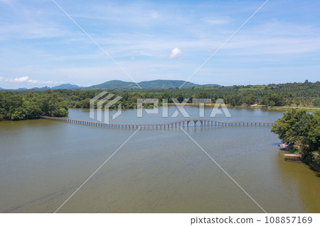 Aerial top view of a bridge with garden park with green mangrove forest trees, river, pond or lake. Nature landscape background, Thailand. Aerial top view of a bridge with garden park with green mangrove forest trees, river, pond or lake. Nature landscape background, Thailand. 108857169
