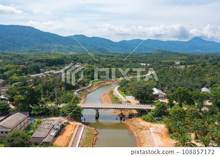 Aerial top view of a bridge with garden park with green mangrove forest trees, river, pond or lake. Nature landscape background, Thailand. Aerial top view of a bridge with garden park with green mangrove forest trees, river, pond or lake. Nature landscape background, Thailand. 108857172