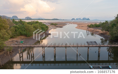 Aerial top view of a bridge with garden park with green mangrove forest trees, river, pond or lake. Nature landscape background, Thailand. 108857176