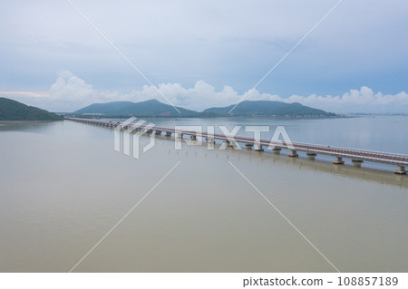 Aerial top view of a bridge with garden park with green mangrove forest trees, river, pond or lake. Nature landscape background, Thailand. Aerial top view of a bridge with garden park with green mangrove forest trees, river, pond or lake. Nature landscape background, Thailand. 108857189