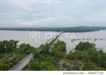Aerial top view of a bridge with garden park with green mangrove forest trees, river, pond or lake. Nature landscape background, Thailand. 108857198