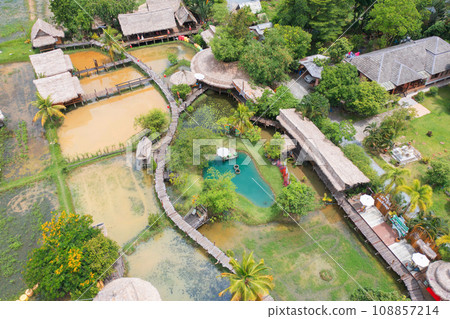 Aerial top view of a bridge with garden park with green mangrove forest trees, river, pond or lake. Nature landscape background, Thailand. Aerial top view of a bridge with garden park with green mangrove forest trees, river, pond or lake. Nature landscape background, Thailand. 108857214