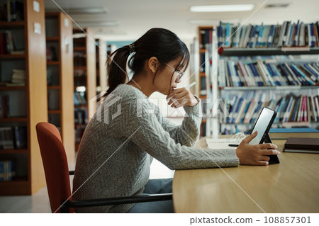 Asian student woman read books in library at university. Young girl stress tired have problem while study hard. Sadness concept 108857301
