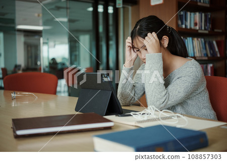 Asian student woman read books in library at university. Young girl stress tired have problem while study hard. Sadness concept 108857303
