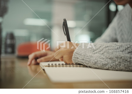 Student preparing for college test, exam, reading book, studying textbook, writing notes, making summary for class report. Learning workplace table, hands with pencil close up Student preparing for college test, exam, reading book, studying textbook, writing notes, making summary for class report. Learning workplace table, hands with pencil close up 108857416