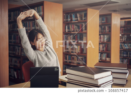 Student girl reading and doing stretch oneself in library of university or colleage. Student girl reading and doing stretch oneself in library of university or colleage. 108857417