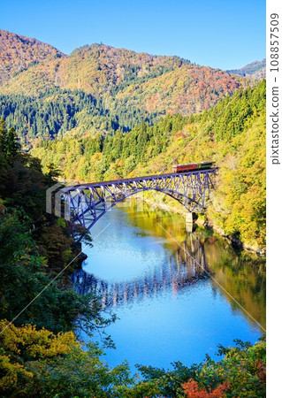 Tadami Line - Train crossing the Daiichi Tadami River Bridge in autumn (Mishima Town, Fukushima Prefecture, afternoon in late October) 108857509