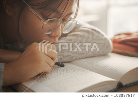 Boring student girl lying on book and reading book, Student girl at boring lesson feeling tired or depressed. Boring student girl lying on book and reading book, Student girl at boring lesson feeling tired or depressed. 108857617