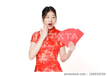 Surprised Asian woman wearing traditional cheongsam qipao dress holding angpao or red packet monetary gift isolated on white background. Happy Chinese new year. Surprised Asian woman wearing traditional cheongsam qipao dress holding angpao or red packet monetary gift isolated on white background. Happy Chinese new year. 108858108