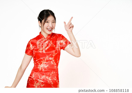 Happy Asian woman wearing traditional cheongsam qipao dress hand pointing up to copy space isolated on white background. Happy Chinese new year 108858118