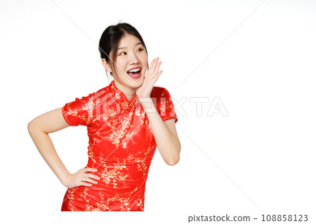 Asian woman wearing traditional cheongsam qipao dress with gesture shouting and holding palm near opened mouth isolated on white background. Happy Chinese new year. Asian woman wearing traditional cheongsam qipao dress with gesture shouting and holding palm near opened mouth isolated on white background. Happy Chinese new year. 108858123
