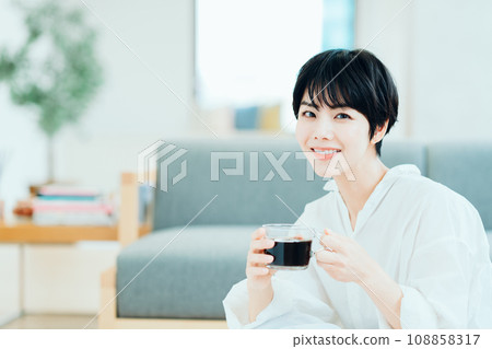 A woman drinking coffee in the living room. A woman drinking coffee in the living room. 108858317
