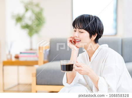一個女人在客廳喝咖啡。 一個女人在客廳喝咖啡。 108858328