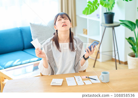 A young woman with a surprised expression holding a receipt in her hand A young woman with a surprised expression holding a receipt in her hand 108858536