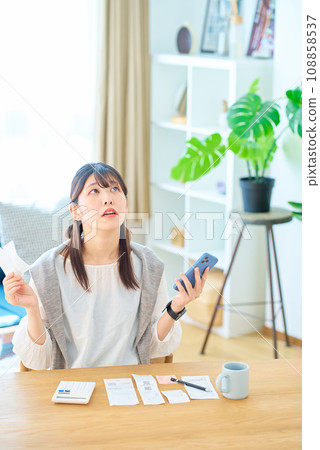 A young woman with a surprised expression holding a receipt in her hand A young woman with a surprised expression holding a receipt in her hand 108858537