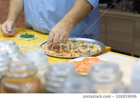 Sushi chef placing toppings on sushi rolls Sushi chef placing toppings on sushi rolls 108859096