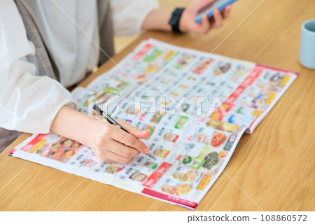 Hand of a woman checking an advertising booklet 108860572