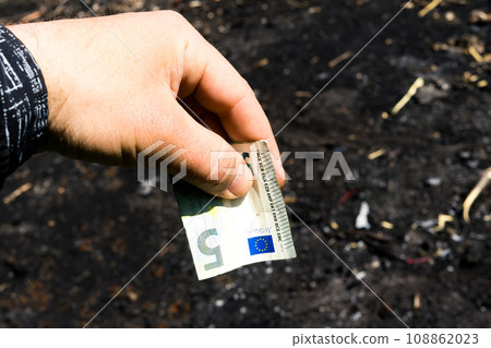 Coin and banknotes on black hot coal among ashes. Currency devaluated, finance and business concept Coin and banknotes on black hot coal among ashes. Currency devaluated, finance and business concept 108862023