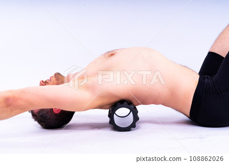Athlete massaging and stretching iliotibial ban muscle with foam roller. Athlete massaging and stretching iliotibial ban muscle with foam roller. 108862026