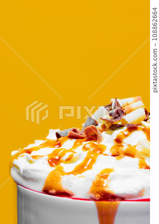 Close-up of delicious sweet drink with whipped cream and caramel toppings against yellow background. Poster 108862664