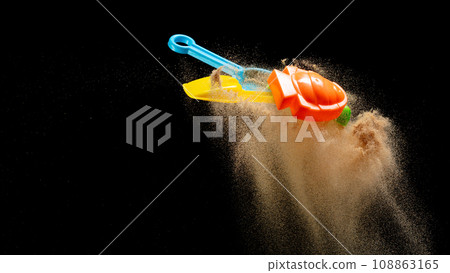 Sand beach plastic Toy for kid to play along ocean sea beach is red blue yellow green. Digging Molding toy fly with sand in air, Kid enjoy playing colorful toy. Black background isolated 108863165