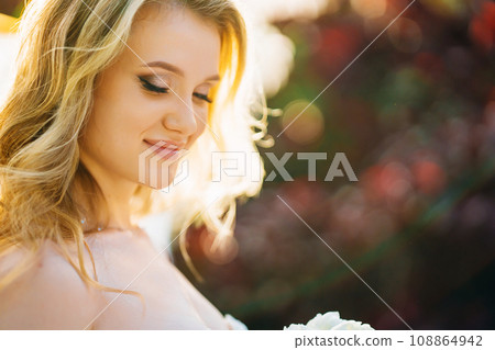 Delicate portrait of a blonde bride in the rays of the setting sun.  108864942