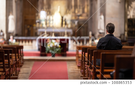 A man sitting in a church looking at the alter 108865353