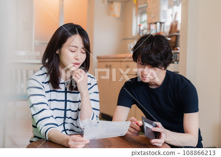 一對年輕夫婦查看賬單詳細信息,發現價格上漲。 一對年輕夫婦查看賬單詳細信息,發現價格上漲。 108866213