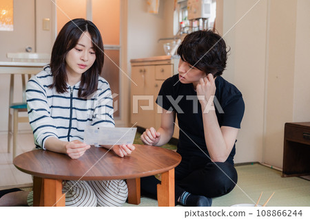 一對年輕夫婦查看賬單詳細信息,發現價格上漲。 一對年輕夫婦查看賬單詳細信息,發現價格上漲。 108866244