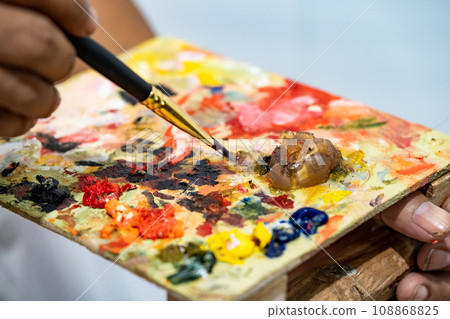 The artist is doing oil painting with many colors on a wood plate. The artist is doing oil painting with many colors on a wood plate. 108868825