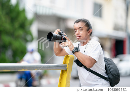 Professional Asian Camera man focus on the image with his mirrorless camera beside the street outdoor field. 108869581