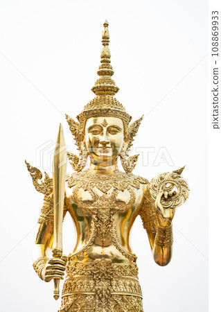 A golden graven image standing with a sword and rowel in his hand. Jada's multiple layers are placed on his head. He was standing on golden bases against a white backdrop A golden graven image standing with a sword and rowel in his hand. Jada's multiple layers are placed on his head. He was standing on golden bases against a white backdrop 108869933