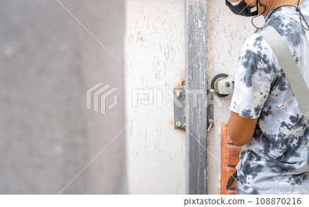 Asian worker young man sawing and kept detailed metal screw from a steel pole for preparing to install foam brick wall. 108870216