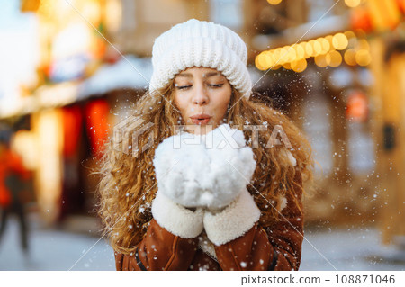 A young woman walks through a Christmas market decorated with festive decorations and lights. 108871046