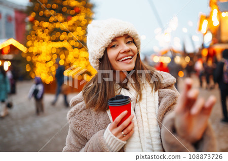 Young woman in winter style clothes posing at festive street market. Woman enjoying winter moments. Young woman in winter style clothes posing at festive street market. Woman enjoying winter moments. 108873726