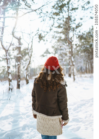 Happy woman standing among snowy trees and enjoying first snow. Holidays, rest, travel concept 108874050