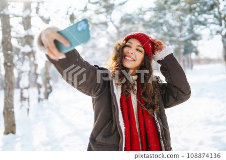 Happy woman taking selfie in winter forest. Young tourist with phone. Selfie time. lifestyle. Happy woman taking selfie in winter forest. Young tourist with phone. Selfie time. lifestyle. 108874136