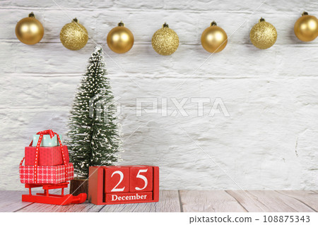 Decorative Christmas tree and red wooden perpetual calendar with date on white brick background. 108875343