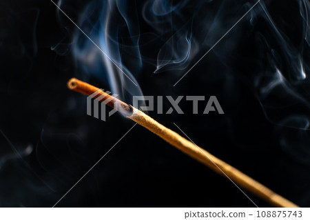 Smoke from a burning aroma stick on a black background. Incense sticks, aromatherapy and meditation. 108875743
