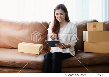 Starting small business entrepreneur of independent young Asian woman online seller is using tablet computer and taking orders to pack products for delivery to customers. SME delivery concept. 108875936