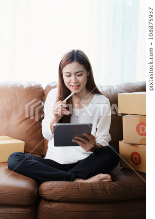 Starting small business entrepreneur of independent young Asian woman online seller is using tablet computer and taking orders to pack products for delivery to customers. SME delivery concept. Starting small business entrepreneur of independent young Asian woman online seller is using tablet computer and taking orders to pack products for delivery to customers. SME delivery concept. 108875937